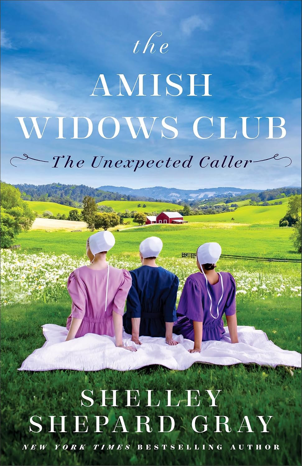 Cover of "The Amish Widows Club: The Unexpected Caller" by Shelley Shepard Gray. Three Amish women in bonnets sit on a blanket in a field, gazing over green hills toward a red barn.